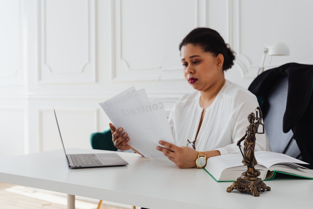 Black woman lawyer reading legal papers at her desk in a modern office.