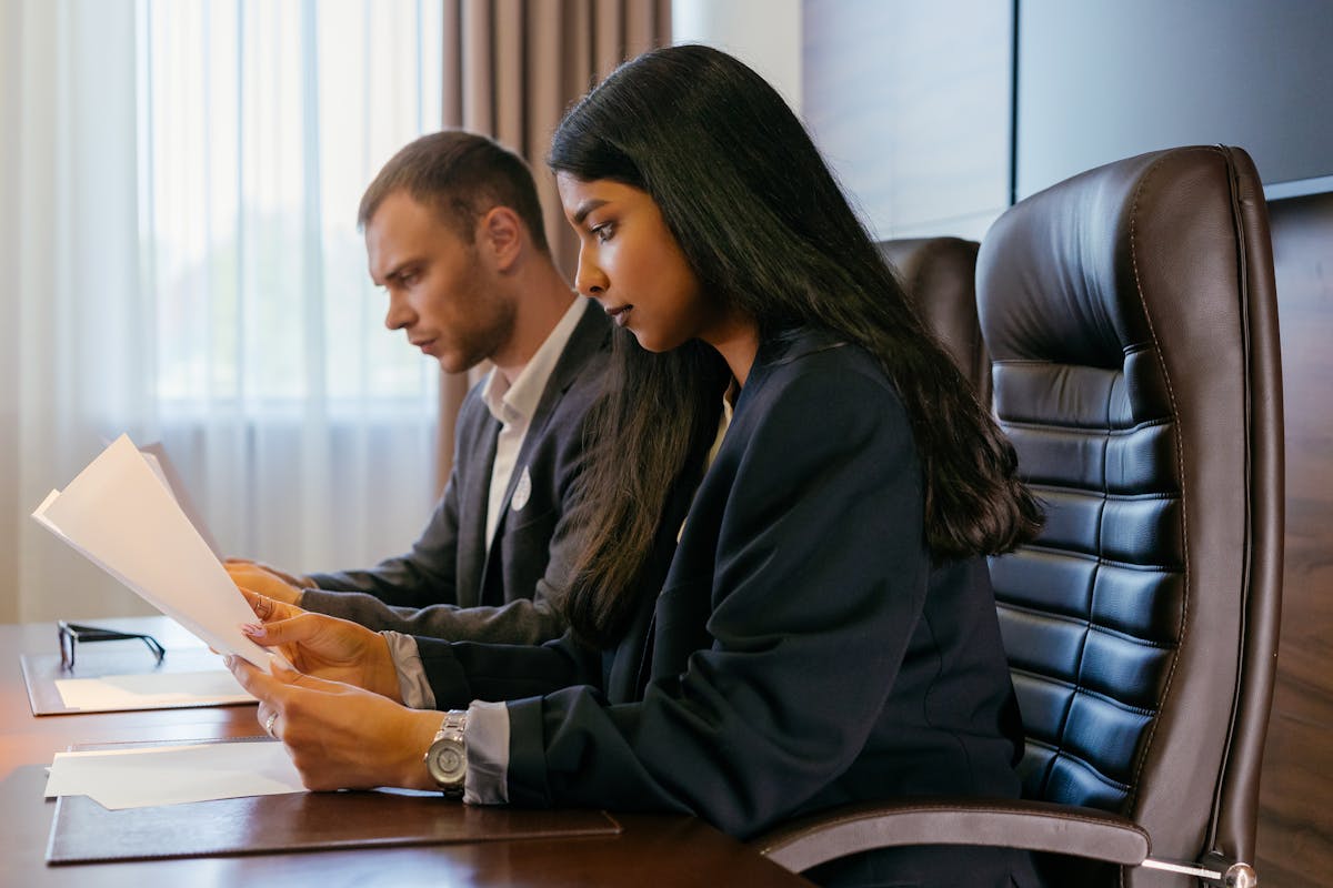 Two professionals reviewing documents in an office setting, showcasing teamwork and diversity.