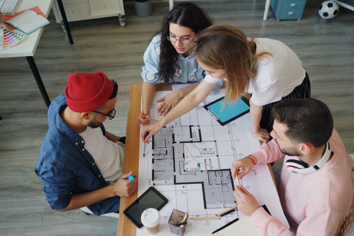 Young creative professionals discussing an architectural blueprint in a modern office setting.