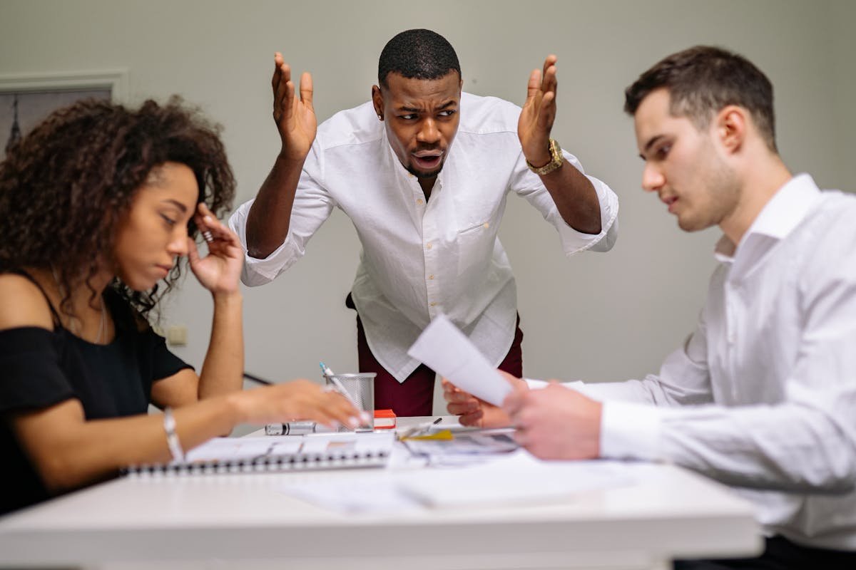 Three colleagues in a heated argument at the office, highlighting workplace stress.