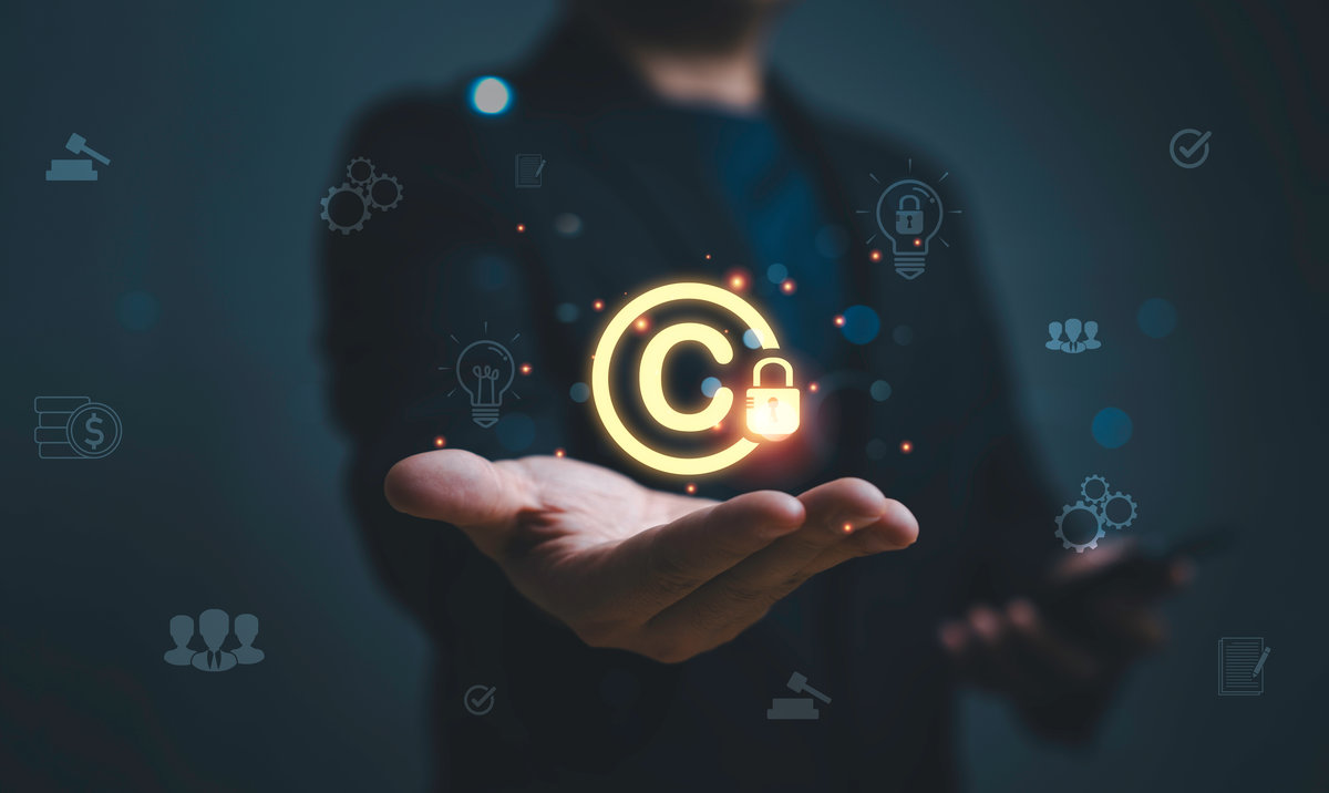 Businessman holding glowing copyright symbol with lock representing intellectual property protection, digital rights management security, online content ownership and legal protection concept.